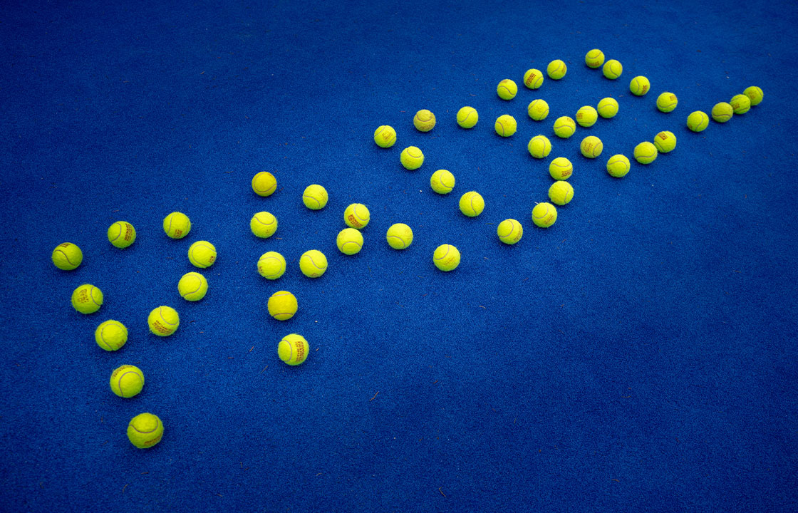 Boden eines Padle-Courts, auf dem Padel Bälle in Form der Buchstaben des Worts "Padel" angeordnet sind.