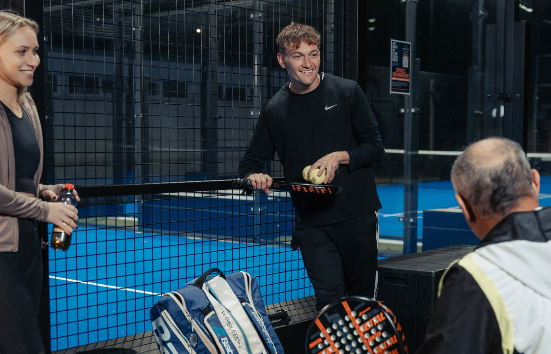 Mehrere Personen unterhalten sich während einer Padel Pause