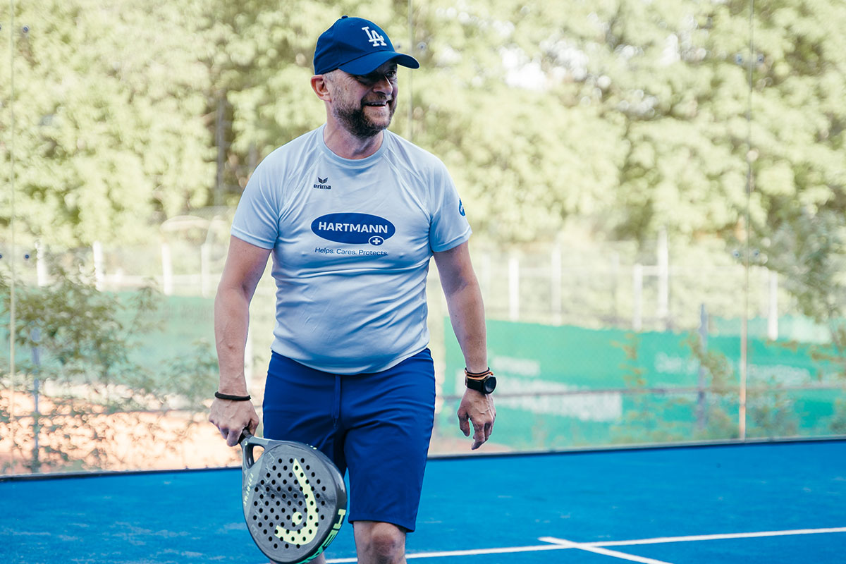 Ein lächelnder Mann, der auf dem Padel Court läuft.