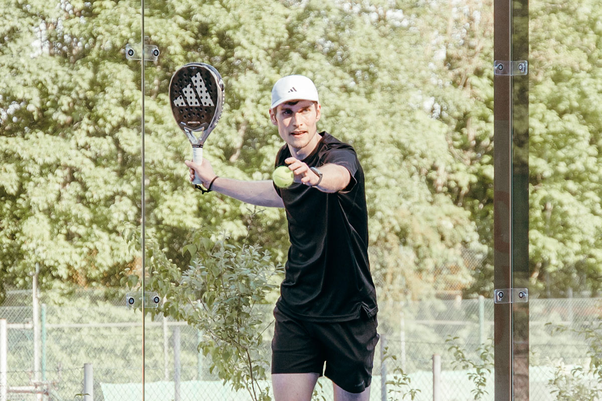 Ein Mann, der beim Padel den Aufschlag macht.